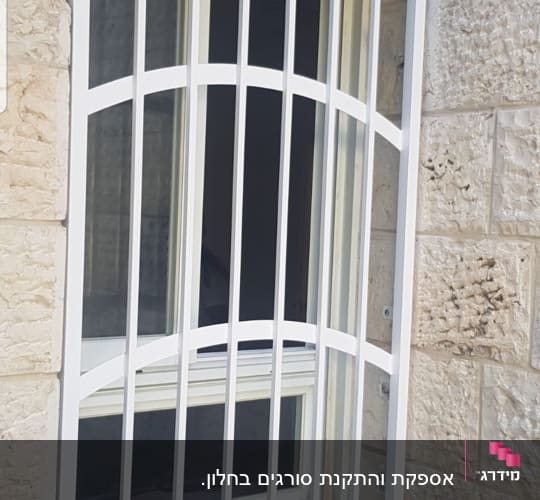 סורגי מתכת לבנים על חלון זכוכית